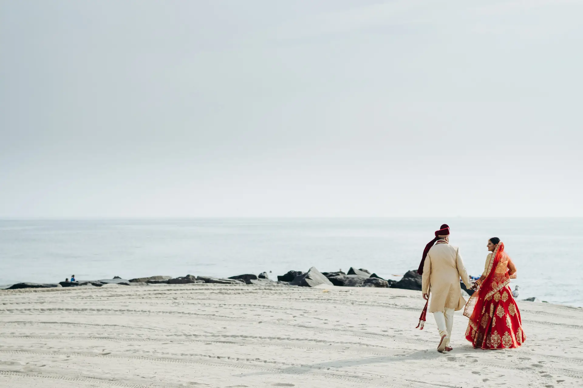 Hindu wedding couple walks along the ocean shore