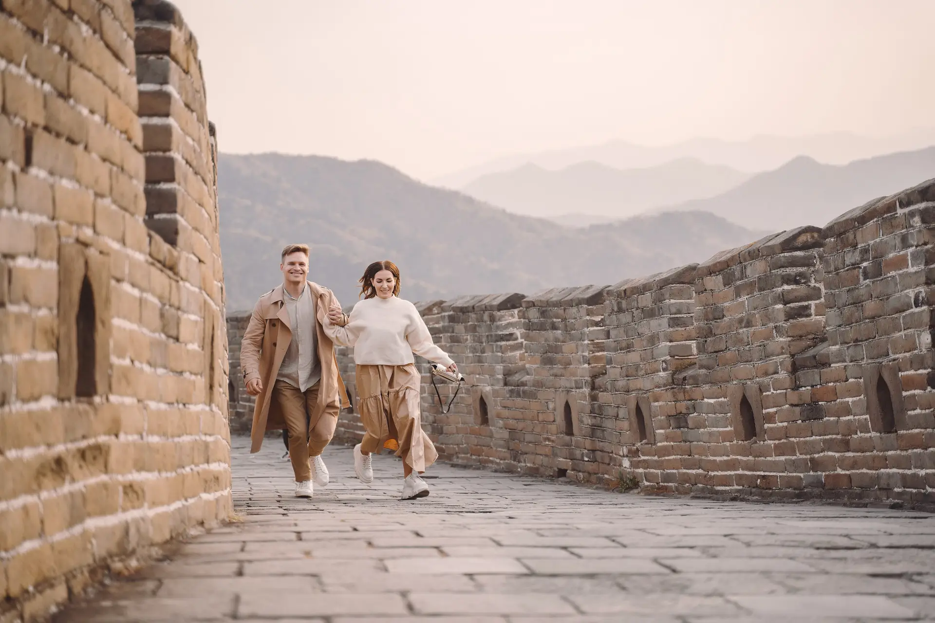 young couple running and twirling at the Great Wall of China. Newly married couple on their honeymoon to the Great Wall of China near Beijing China.